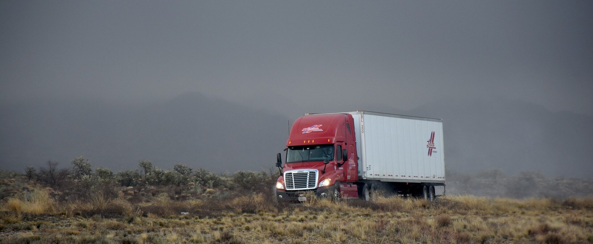 Semi truck and trailer driving through dessert terrain