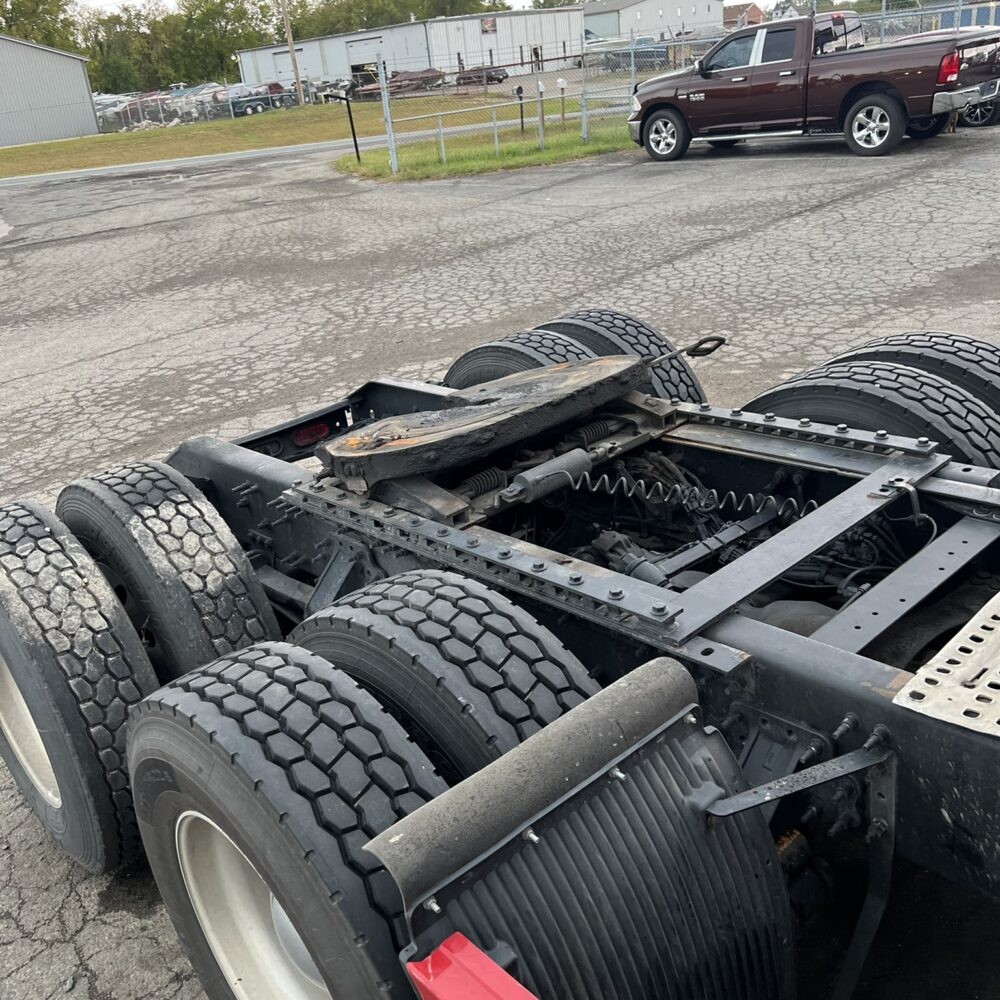 A close-up view of the rear tandem axle assembly of a semi truck, showing the tires and fifth-wheel hitch.