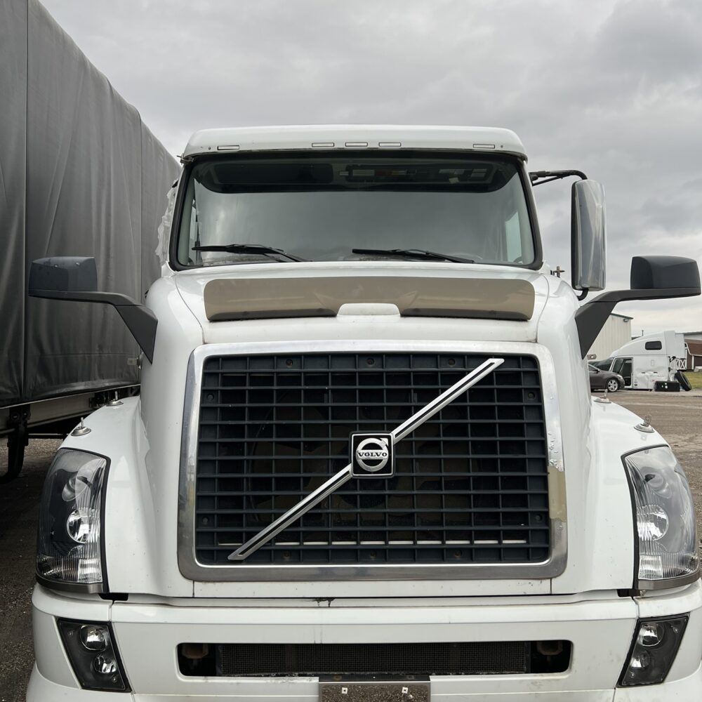 Close-up head-on view of a white Volvo semi truck grille.