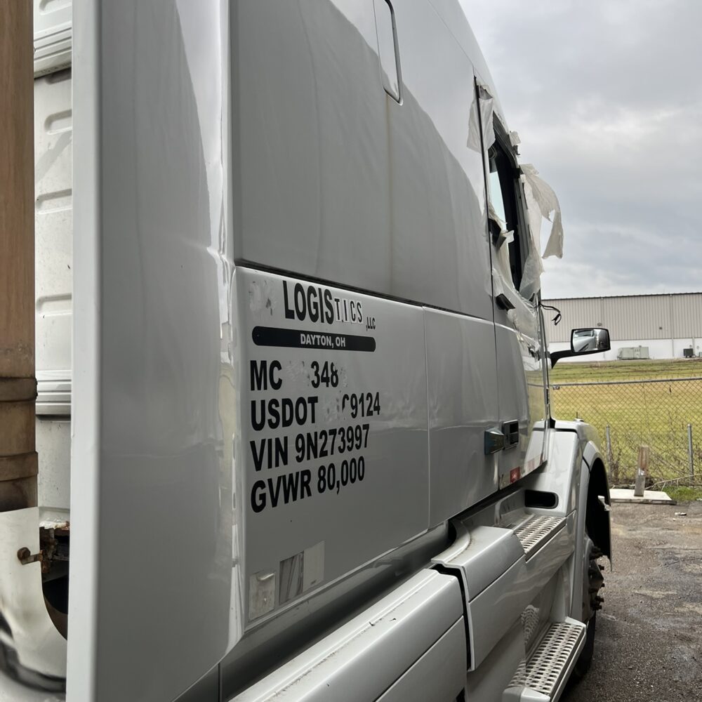 Side profile of Volvo semi truck with visible damage.