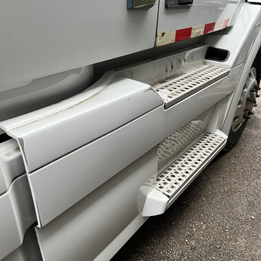 Close-up of Volvo semi truck steps and lower body panel.