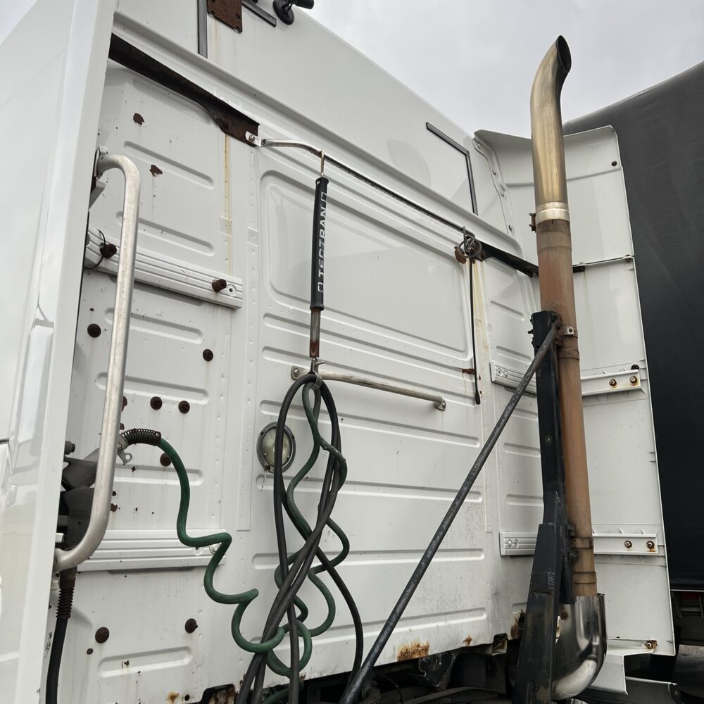 Exhaust stack and cables on Volvo semi truck rear section.