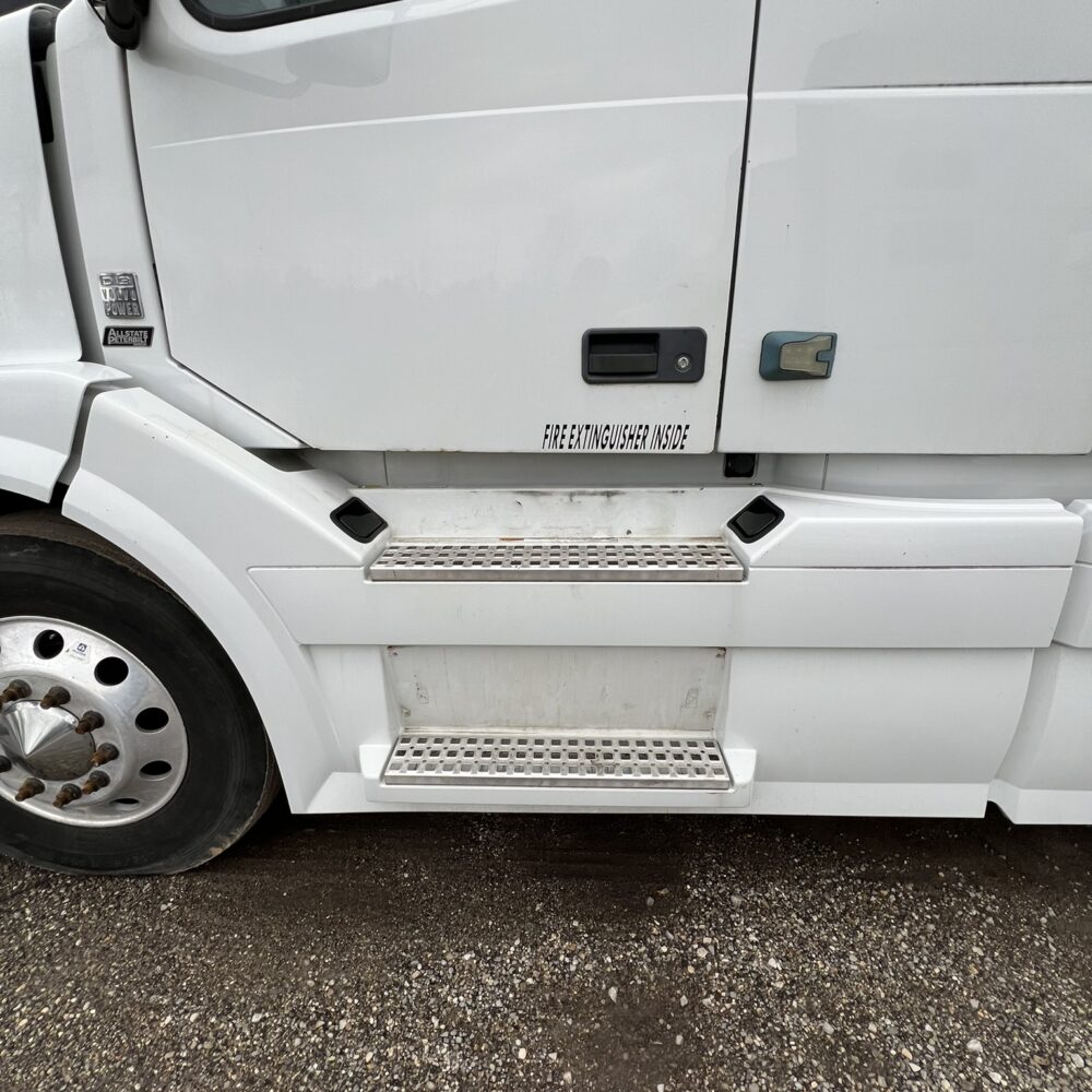 Steps on the driver side of a white Volvo semi truck.
